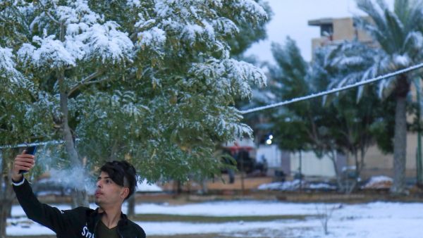 An Iraqi youth poses for a selfie in the snow in the holy Shiite city of Karbala on February 11, 2020. Iraq's capital Baghdad woke up covered in a thin layer of fresh snow, an extremely rare phenomenon for one of the world's hottest countries. Snow also covered the Shiite holy city of Karbala further south and Mosul in the north, where heavier precipitation left a blanket of snow over the city's centuries-old ruins.  Mohammed SAWAF / AFP
