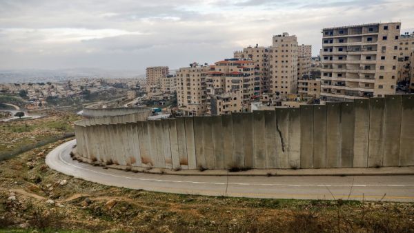 A picture taken on February 11, 2020 shows the Israeli settlement of Pisgat Zeev (L), built in a suburb of the mostly Arab east Jerusalem, and the Palestinian Shuafat refugee camp (R) behind Israel's controversial separation wall. AHMAD GHARABLI / AFP