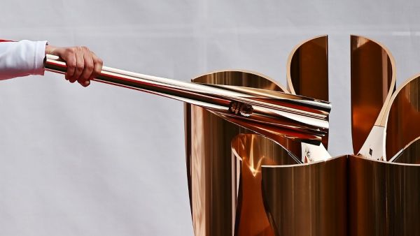 A runner holding an Olympic torch practices lighting a cauldron during a rehearsal of the Tokyo 2020 Olympics torch relay in Tokyo on Feb 15, 2020. CHARLY TRIBALLEAU / AFP