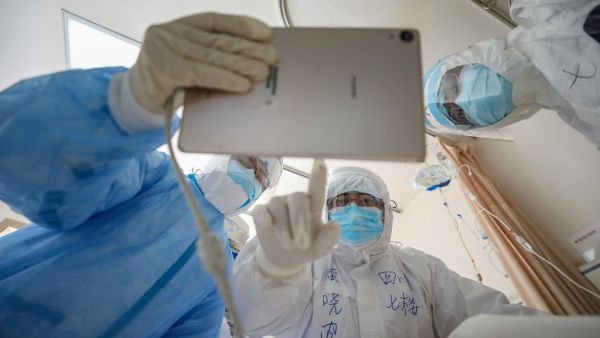 This photo taken on February 16, 2020 shows a doctor looking at an image as he checks a patient who is infected by the COVID-19 coronavirus at the Wuhan Red Cross Hospital in Wuhan in China's central Hubei province. The death toll from the COVID-19 coronavirus epidemic jumped to 1,770 in China after 105 more people died, the National Health Commission said February 17. STR / AFP
