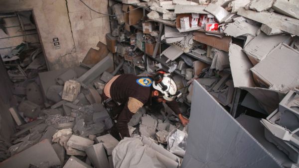 A member of the Syrian Civil Defence, also known as the "White Helmets", inspects through debris and rubble while searching for survivors at a destroyed hospital in the town of Darret Ezza, about 30 kilometres northwest of the northern Syrian city of Aleppo on February 17, 2020, after a reported air strike hit the building. AAREF WATAD / AFP