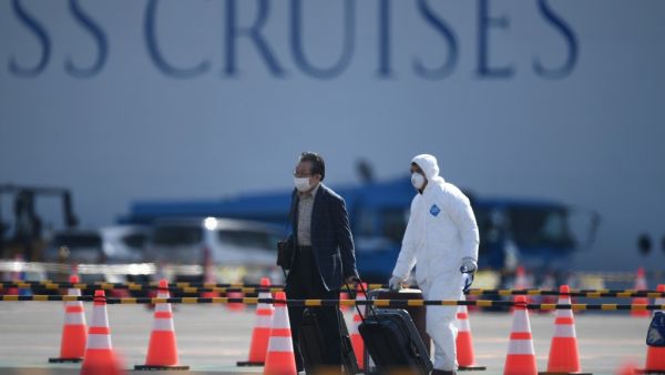 A passenger (L) disembarks from the Diamond Princess cruise ship - in quarantine due to fears of the new COVID-19 coronavirus - at the Daikoku Pier Cruise Terminal in Yokohama on February 19, 2020. AFP