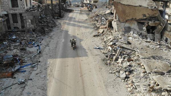 An aerial view taken on February 19, 2020 shows a man riding his motorcycle through destroyed buildings in the Syrian town of Ihsim in the southern countryside of Idlib. Omar HAJ KADOUR / AFP