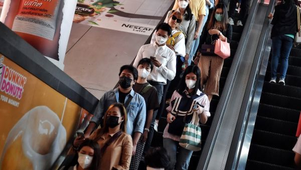 This photo taken on February 18, 2020 shows people wearing protective facemasks, amid concerns of the COVID-19 coronavirus outbreak, as they ride on an escalator during the morning commute in Bangkok. Lillian SUWANRUMPHA / AFP