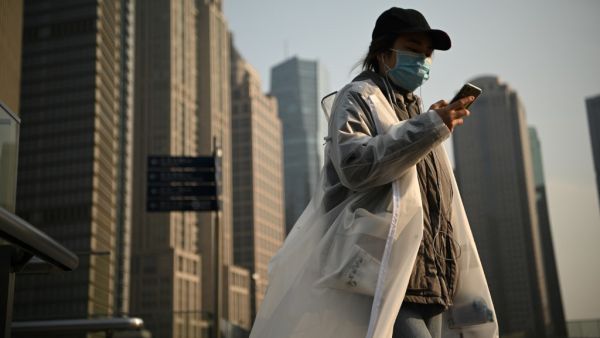 People wearing protective face masks walk on an overpass in Shanghai on February 24, 2020. China is expected to decide February 24 whether to postpone its annual parliament session for the first time since the Cultural Revolution as the country battles the COVID-19 coronavirus outbreak. Noel Celis / AFP
