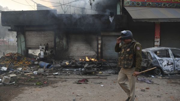 A policeman walks past a burnt vehicle following clashes between supporters and opponents of a new citizenship law, at Bhajanpura area of New Delhi on February 24, 2020, ahead of US President arrival in New Delhi. AFP/File