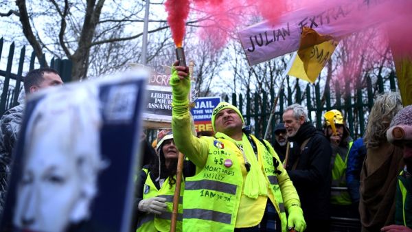 A supporter of WikiLeaks founder Julian Assange, wearing a French themed "yellow vest" or gilets jaunes, holds a flare as he calls for Assange's freedom outside Woolwich Crown Court and HMP Belmarsh prison in southeast London on February 24, 2020, on the opening day of the trial to hear a US request for Assange's extradition. AFP