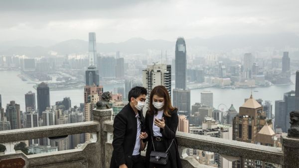 People wearing protective face masks visit the lookout of Victoria Peak in Hong Kong on February 25, 2020. The new coronavirus has peaked in China but could still grow into a pandemic, the World Health Organization warned, as infections mushroom in other countries. ISAAC LAWRENCE / AFP