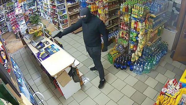 The man, who was seen wearing a balaclava, entered the shop before pulling out a gun and approaching the woman as she mopped the floors. (Video Screenshot)