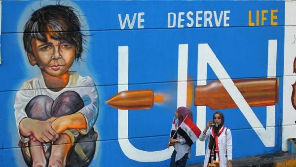Iraqi protesters walk in front of a mural painting in Tahrir square in Baghdad on November 13, 2019. (AFP)