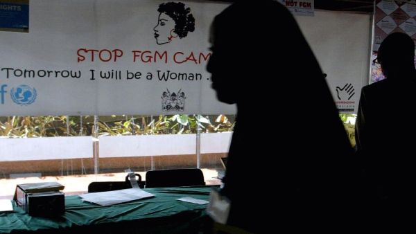 A young woman walks past a banner against female genital mutilation (AFP Photo/SIMON MAINA)