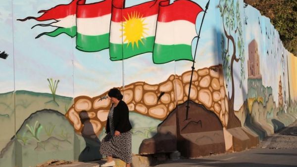 A woman walks passed a mural depicting the Kurdish flag in Erbil. (AFP)