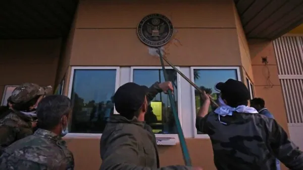Iraqi supporters and members of the Popular Mobilization Forces paramilitary pull off a plaque from the entrance of the US embassy in Baghdad, Iraq, December 31, 2019. (Ahmad al-Rubaye/AFP)