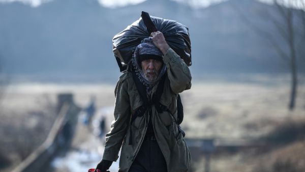 A migrant carries his belongings as he walks toward Meritsa river, near Edirne, to take a boat to attempt to enter Greece by crossing the river on March 1, 2020. AFP