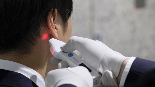 A visitor to the Tokyo Metropolitan Government office has his body temperature checked at the reception of the building in Tokyo on March 5, 2020. Japan will quarantine all passengers arriving from China and South Korea, the country's prime minister said on March 5, as the government ramps up measures to contain an outbreak of the COVID-19 coronavirus. Kazuhiro NOGI / AFP