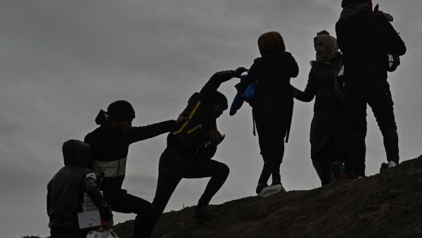 Migrants climb a hill as they gather near the Tunca river in the city of Edirne, northwest Turkey on March 5, 2020 waiting to resume their efforts to enter Europe near Pazarkule border gate. EU members on March 4, 2020 rejected what they said is Turkey's use of desperate migrants to pressure its neighbours -- and strongly backed Greece's border crackdown. The EU has scrambled to respond to the surge of migrants at the Greek border, where authorities say some 24,000 were stopped from entering between Februar