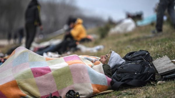 A migrant rests on the grass verge as they gather near the Tunca river waiting to resume their efforts to enter Europe near Pazarkule border gate in the city of Edirne, northwest Turkey on March 5, 2020. EU members on March 4, 2020 rejected what they said is Turkey's use of desperate migrants to pressure its neighbours -- and strongly backed Greece's border crackdown. The EU has scrambled to respond to the surge of migrants at the Greek border, where authorities say some 24,000 were stopped from entering be