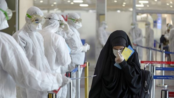 Medical staff in protective gears distribute information sheets to Iraqi passengers returning from Iran at Najaf International Airport on March 5, 2020. Iraqi health authorities announced the country's first two deaths from the new coronavirus, one in the capital Baghdad and the other in the autonomous Kurdish region. Haidar HAMDANI / AFP
