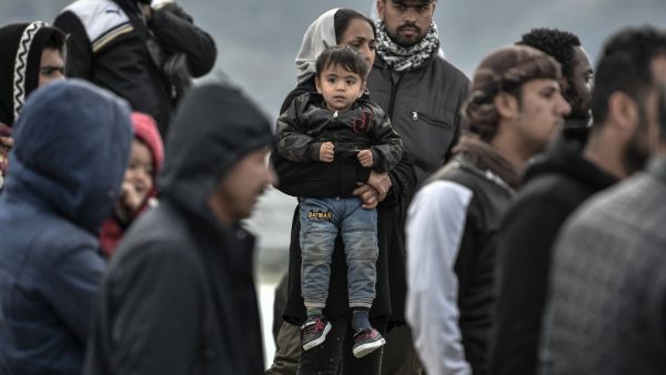 Refugees and migrants who arrived on Lesbos island after March 1, stand in the port of Mytilene next to the military carrier which accomodates them on the island of Lesbos on March 7, 2020. Over 1,700 migrants have landed on Lesbos and four other Aegean islands from Turkey over the past week, adding to the 38,000 already crammed into abysmal and overstretched refugee centres. LOUISA GOULIAMAKI / AFP