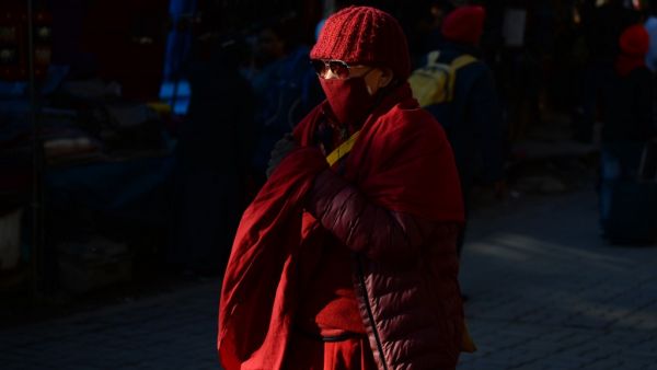 A Buddhist monk wearing facemasks amid fears of the spread of COVID-19 novel coronavirus, walks along a street market in McLeod Ganj near Dharamshala on March 9, 2020. Sajjad HUSSAIN / AFP