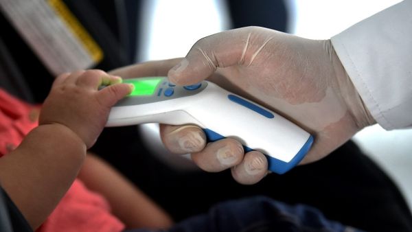 A security member checks the temperature of a passenger as a preventive measure against the spread of the new Coronavirus, COVID-19, at the Bonilla Aragon international airport in Palmira, Colombia, on March 10, 2020. Luis ROBAYO / AFP