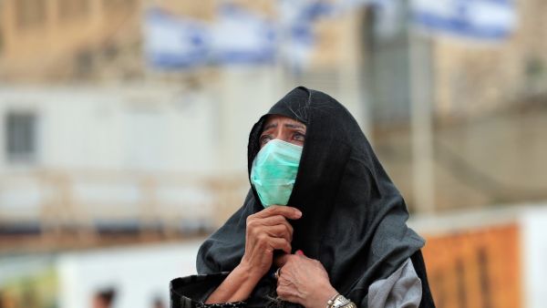 A woman, wearing a protective mask, looks at the nearly deserted Western Wall, Judaism's holiest site, after Israel has imposed some of the world's tightest restrictions to contain COVID-19 coronavirus disease, in Jerusalem on March 12, 2020. Israel imposed a two-week quarantine on all travellers entering the country, almost stopping tourism and limiting public gatherings as officials confirmed its 100th case of the COVID-19 coronavirus disease. Emmanuel DUNAND / AFP