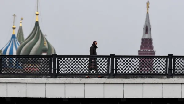 A man walks along a bridge over the Moskva river in front of St. Basil's Cathedral and the Kremlin in downtown Moscow on March 13, 2020. Yuri KADOBNOV / AFP