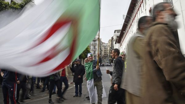 An Algerian protester waves the national flag during a weekly anti-government demonstration in the capital Algiers on March 13, 2020. Algeria has registered two deaths from the novel coronavirus, the health ministry announced, as schools were closed for three weeks. RYAD KRAMDI / AFP