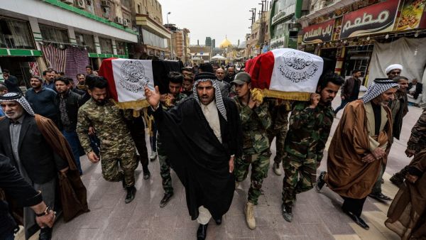 Mourners walk with a coffin draped with the Iraqi national flag defaced with text in Arabic reading "Holy Imam Ali Shrine" during a funerary march for members of the Hashed al-Shaabi (Popular Mobilisation Forces) paramilitaries who were killed in an area targeted by US military air strikes, in the central Iraqi holy shrine city of Najaf on March 14, 2020. AFP/File