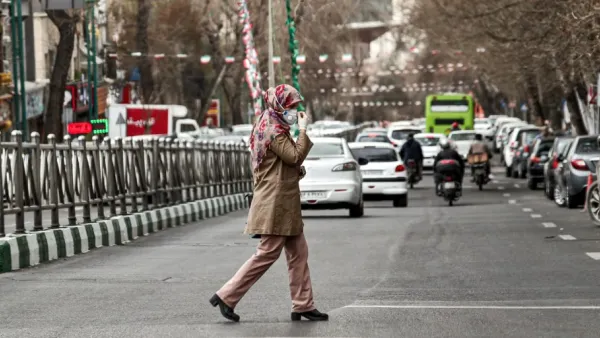A woman wearing a protective face mask and latex gloves crosses a street in Iran's capital Tehran on March 14, 2020. STRINGER / AFP