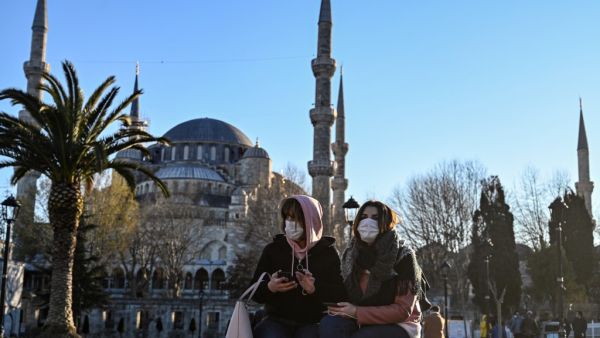 Women wear protective face masks sitting near the Sultanahmet Mosque also known as the Blue Mosque as the nation tries to contain the novel coronavirus, COVID-19, in Istanbul on March 17,2020. OZAN KOSE / AFP