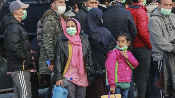 Migrants arrive at the port of Mytilene in the Greek island of Lesbos on March 20, 2020 to be transfered in a closed camp in northern Greece as the country is battling hard to control the novel coronavirus that causes COVID-19 infection and also racing to avoid contagion among tens of thousands of migrants in overcrowded camps nationwide, a situation recently termed a "health bomb" by government spokesman. Manolis Lagoutaris / AFP