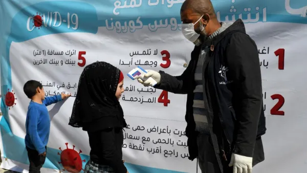 A medical volunteer takes the temperature of a displaced Syrian girl next to a poster, outlining 7 steps to prevent the spread of CONVID-19, at a camp for the internally displaced near Dayr Ballut, near the Turkish border in the rebel-held part of Aleppo province on March 22, 2020, during a campaign to prevent the spread of the virus. Rami al SAYED / AFP