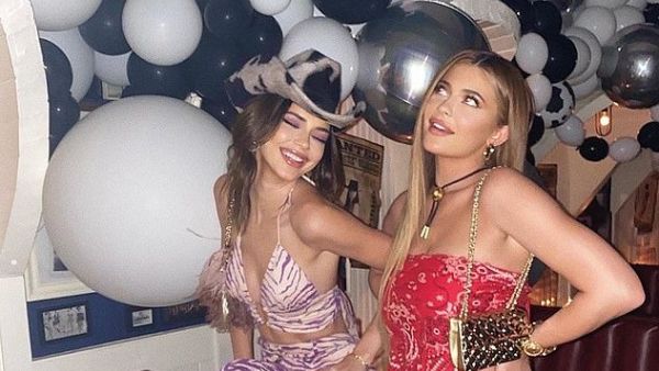 'Howdy': Kylie Jenner flashed her leg while posing with sister Kendall at her pal and former assistant Victoria Villarroel's birthday party on Thursday night (Instagram)