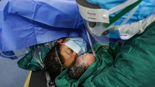 The new mother also wore a mask as her newborn baby girl was gently shown to her by medics in Xiehe hospital, Wuhan (AFP)