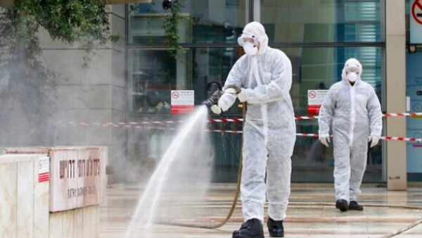 An Israeli firefighter sprays disinfectant at the entrance of Ichilov Hospital in Tel Aviv on March 20, 2020. (Jack Guez/AFP)