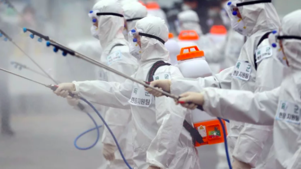 South Korean soldiers wearing protective gear spray disinfectant as part of preventive measures against the spread of the COVID-19 coronavirus, at Dongdaegu railway station in Daegu. -YONHAP/AFP