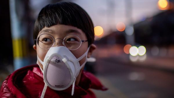 A child, wearing a protective mask to help stop the spread of a deadly virus which began in Wuhan, looks on in a street in Beijing on January 29, 2020. The number of confirmed cases in the new virus outbreak in China reached 5,974 on January 29, overtaking the number of people infected in the mainland by the SARS epidemic in 2002-3, as the death toll rose to 132. NICOLAS ASFOURI / AFP