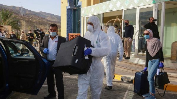 A worker helps a mask-clad woman with her baggage as she prepares to leave a Dead Sea resort where she has been quarantined for 14 days, approximately 60 kilometres sout of the Jordanian capital Amman on March 30, 2020. AFP/File
