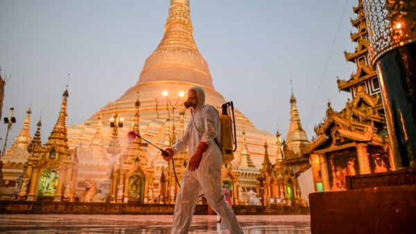 A volunteer sprays disinfectant in Shwedagon Pagoda compound as a preventive measure against the COVID-19 coronavirus, in Yangon on March 31, 2020. Myanmar reported its first coronavirus death -- a 69-year-old man who returned to the country in mid-March after receiving cancer treatment in Australia. Ye Aung Thu / afp