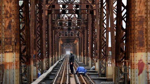 A maintenance worker, wearing a face mask as a preventive measure against the spread of the COVID-19 novel coronavirus, stands in the middle of the railway track on the Long Bien bridge in Hanoi on April 1, 2020. (AFP)