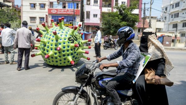 People drive past as inventor Sudhakar Yadav (inside) leads his coronavirus-themed made car on a road for an awareness campaign during a government-imposed nationwide lockdown as a preventive measure against the COVID-19 coronavirus, in Hyderabad on April 8, 2020. NOAH SEELAM / AFP
