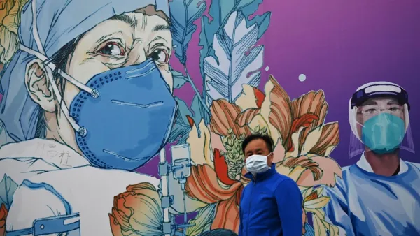 A man wearing a face mask walks in front of a mural at the Leishenshan Hospital that had offered beds for coronavirus patients in Wuhan, in China’s central Hubei province on April 11, 2020. Noel Celis / AFP
