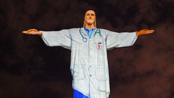 View of the world famous Christ the Redeemer statue on Easter day with a doctor's uniform projected on it in honour of all the medical staff fighting the COVID-9 coronavirus pandemic worldwide in Rio de Janeiro, Brazil on April 12, 2020. CARL DE SOUZA / AFP