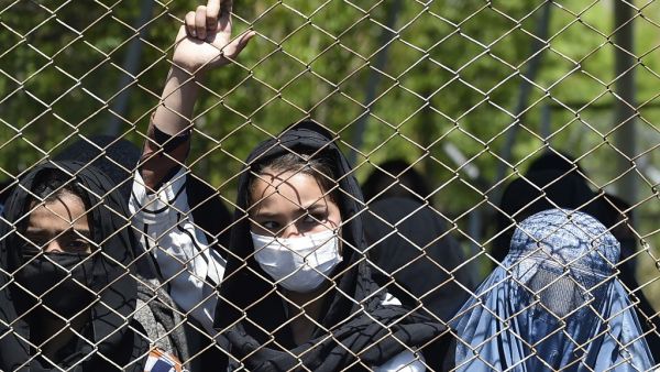 A women wearing a facemask peeks from a iron fence as they wait to receive free wheat from the government emergency committee during a government-imposed lockdown on the capital city as a preventive measure against the COVID-19 coronavirus, in Kabul on April 21, 2020. WAKIL KOHSAR / AFP