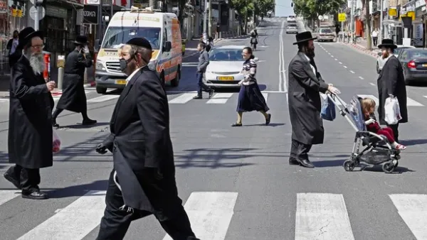 Ultra-Orthodox Jews, some of them wearing masks, cross a street in the religious Israeli city of Bnei Brak, near Tel Aviv, on March 3, 2020 during the novel coronavirus pandemic crisis. (AFP)