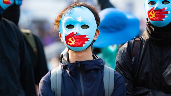 Hong Kong protestors wear masks symbolizing the Communist Party of China's silencing of Uyghur Muslims at a solidarity rally at Edinburgh Place, central Hong Kong. (Shutterstock/ File Photo)