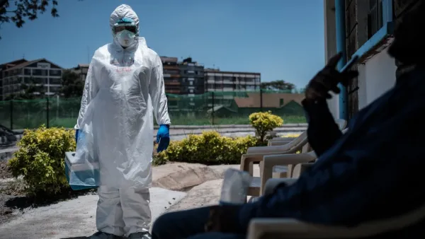 A laboratory specialist wearing protective gear speaks with a man asking to get tested in front of the ward for quarantined people who had close contacts with the first Kenyan patient of the COVID-19 at the Infectious Disease Unit of Kenyatta National Hospital in Nairobi, Kenya, on March 15, 2020. (AFP/File Photo)