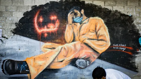 A youth, wearing a protective mask, walks past a mural reading "We are tired" in the Lebanese northern city of Tripoli on April 28, 2020. Lebanon is facing its worst economic crisis since the 1975-1990 civil war, now compounded by a nationwide lockdown to stem the spread of the coronavirus. The Lebanese pound has lost more than half of its value, and prices have soared.This is the case across the country, but Tripoli has been especially hard hit because more than half of its population had already been livi