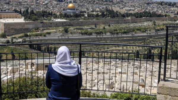 A Palestinian woman looks from the Mount of Olives at the Old City of Jerusalem and the closed-down Aqsa Mosque compound, after the second Friday prayer of the Muslim holy month of Ramadan, on May 1, 2020, amid heightened security and social distancing measures due to the COVID-19 pandemic. AHMAD GHARABLI / AFP